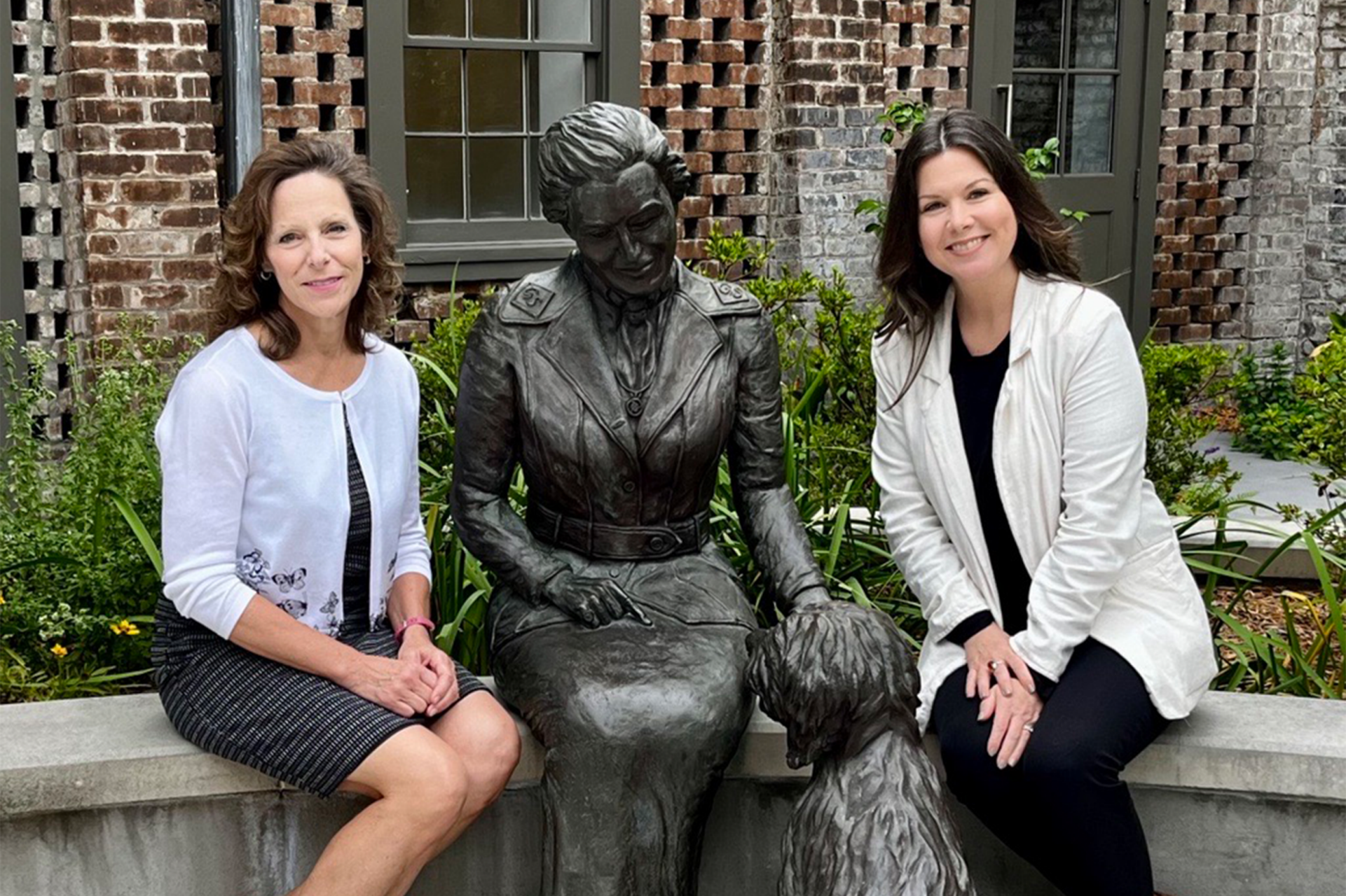 Stacy Cordery and the director of the Birthplace sitting next to a statue of Juliette Gordon Low in the gaden.
