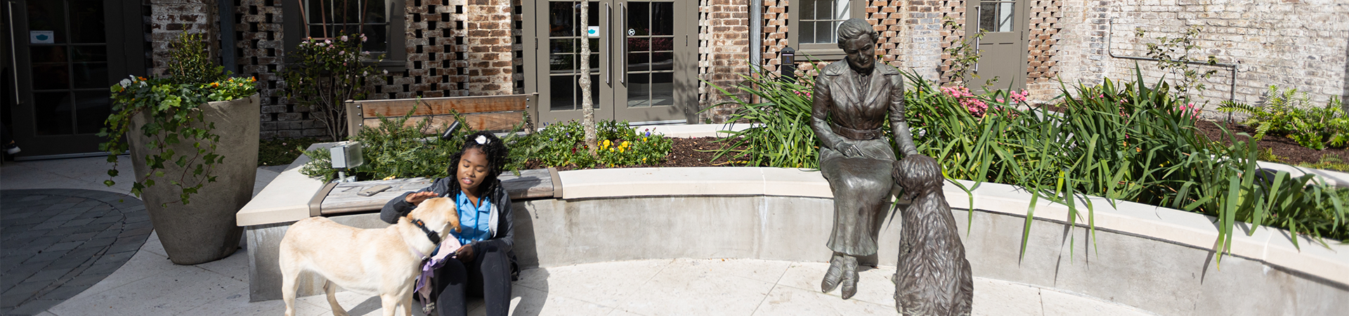  young girl with guide dog sitting next to Juliette Gordon Low statue of her and dog 