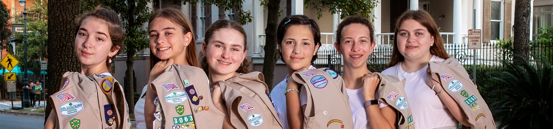  Six Girl Scouts posing with vests over their shoulders outside the Juliette Gordon Low Birthplace Museum. 